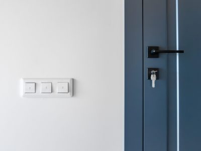Bright wall switches beside a blue door with a black lock and key, clean lines and balanced contrast, a smart home detail in a minimalist scene.